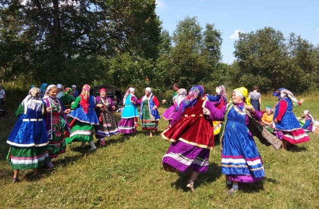 Удмуртки танцуют на лугу в национальных одеждах