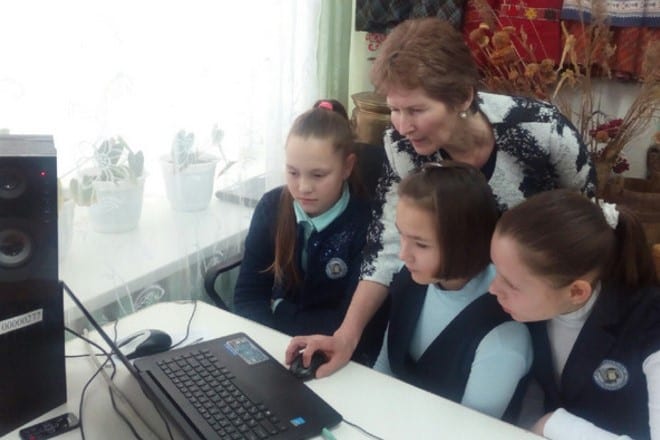 Фото женщина показывает девочкам презентацию на компьютере на удмуртском языке