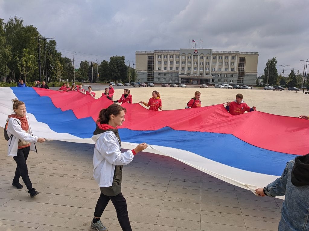 Фото волонтёры несут огромный флаг россии перед зданием правительства в ижевске
