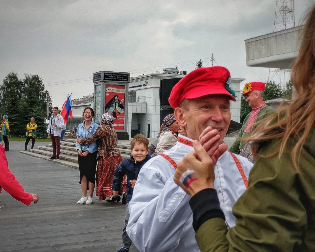 Фото мужчина в красной шапке танцует на дне флага рф