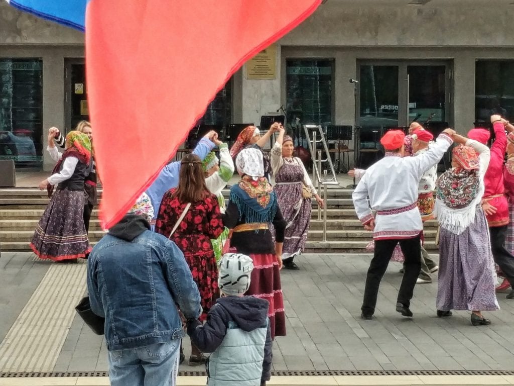 Фото люди танцуют на дне государственного флага россии, флаг развевается на переднем плане