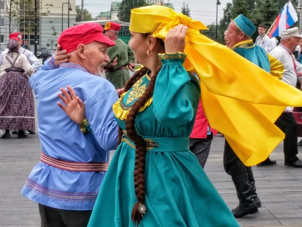 Фото мужчина в национальном русском костюме и женщина в национальном татарском костюме танцуют вместе