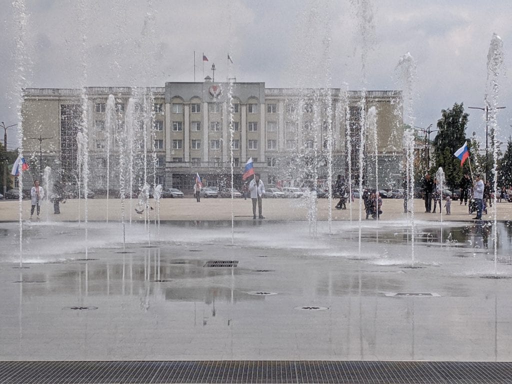 Фото музыкального фонтана у театра оперы и балета, люди ходят с большими флагами россии