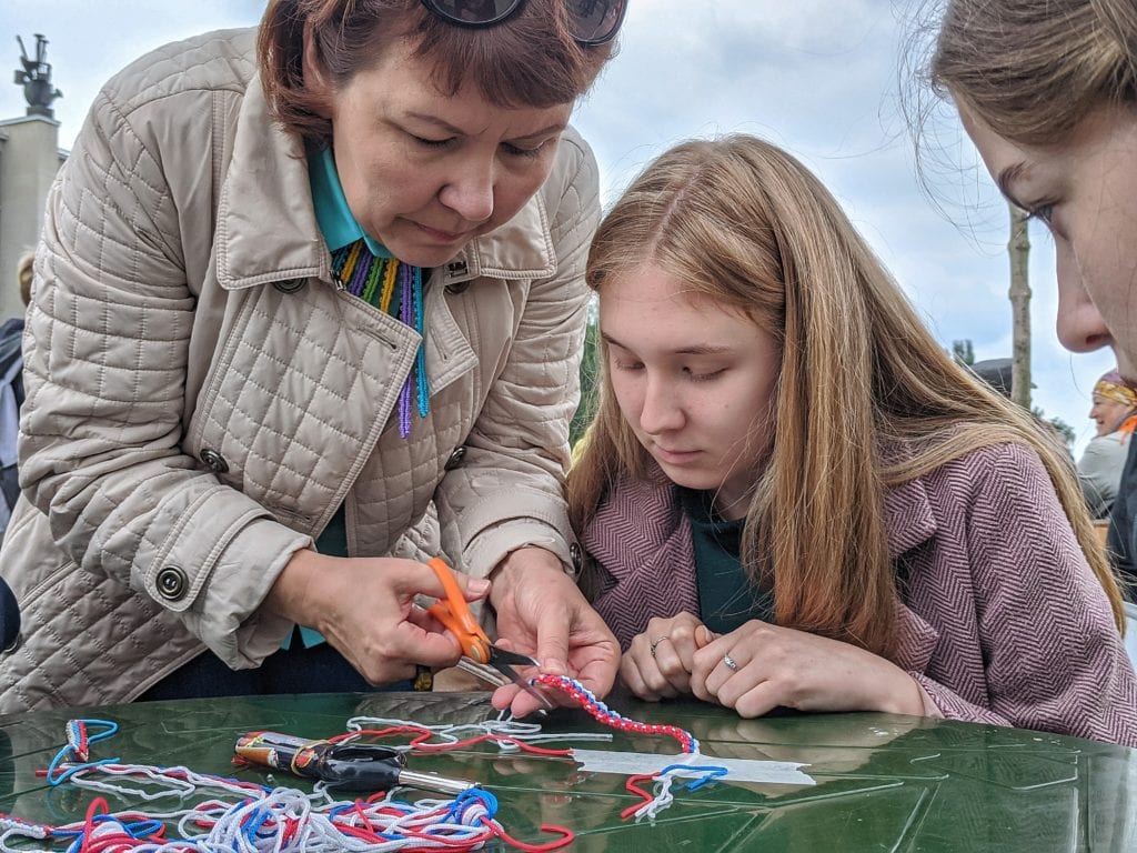 Фото наталья шергина помогает девушке в изготовление браслета цвета флага россии