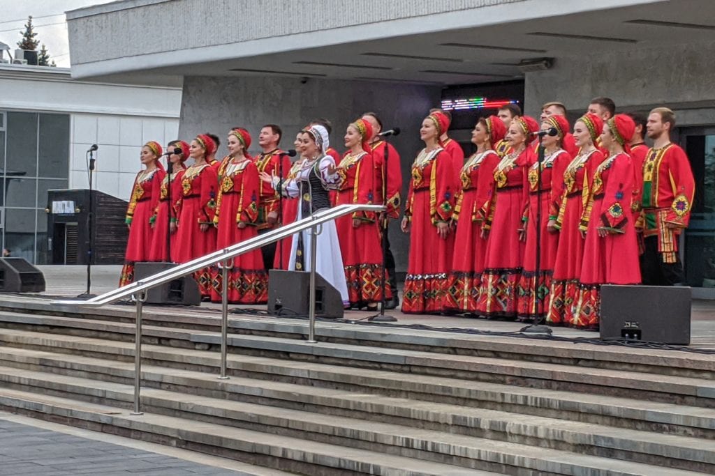 Фото женщины в красных одеждах выступают рядом с театром оперы и балета в ижевске