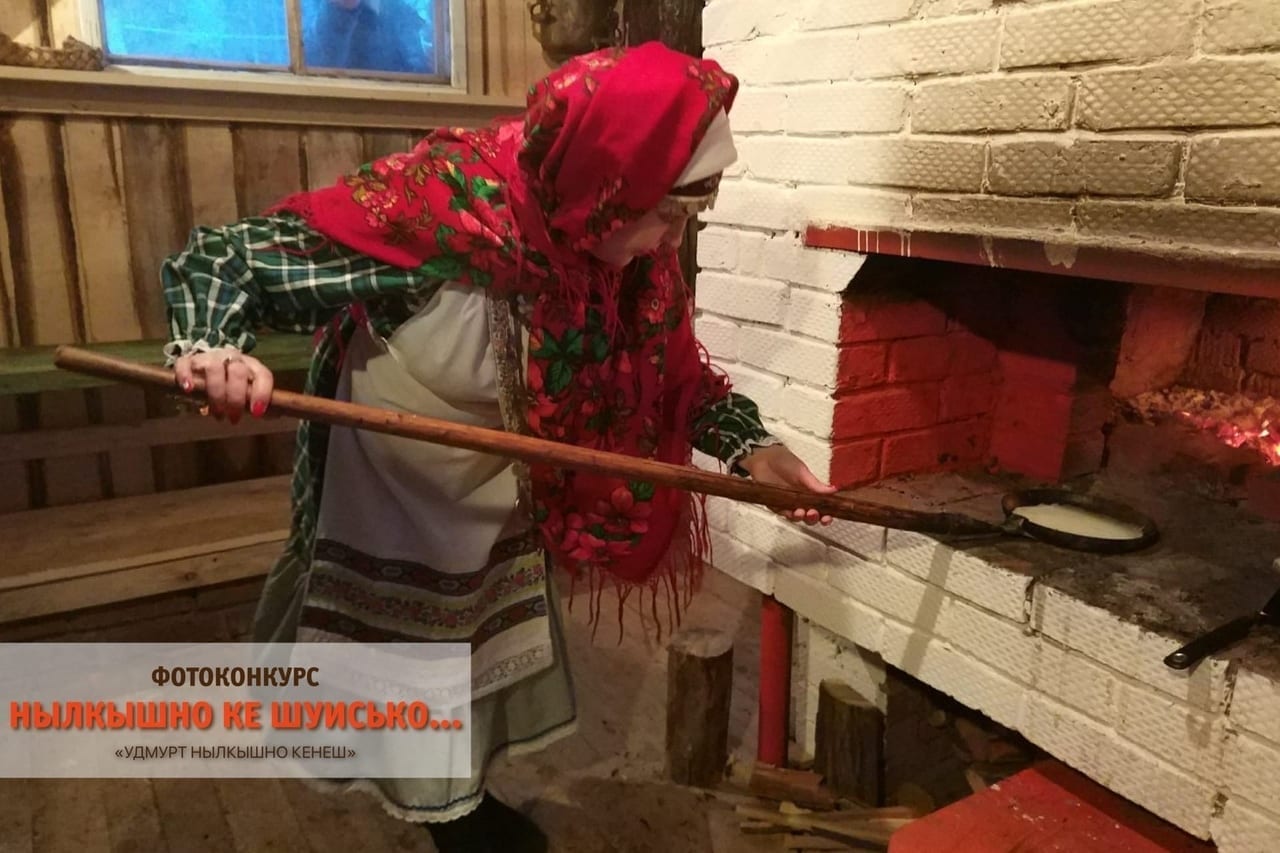 Фото женщина в фартуке с платком ставит ухватом в русскую печь табань
