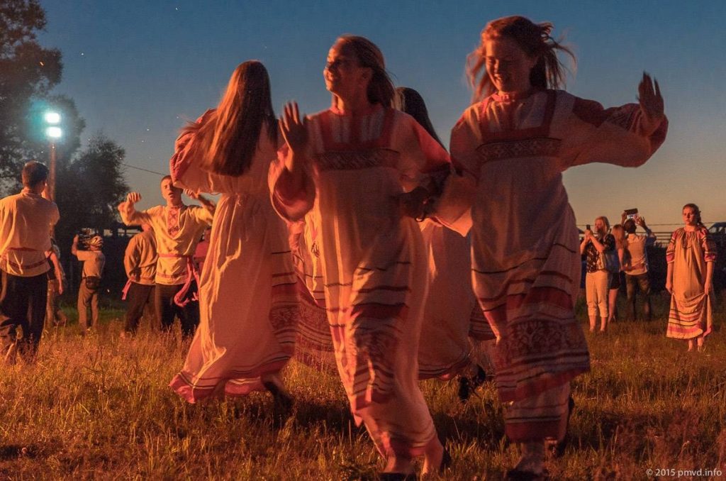 Девушки в традиционных одеждах кружатся в танце в день ивана купала