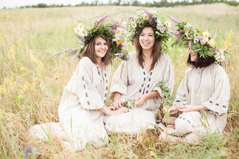 Девушки сидят в поле с цветочными венками на головах